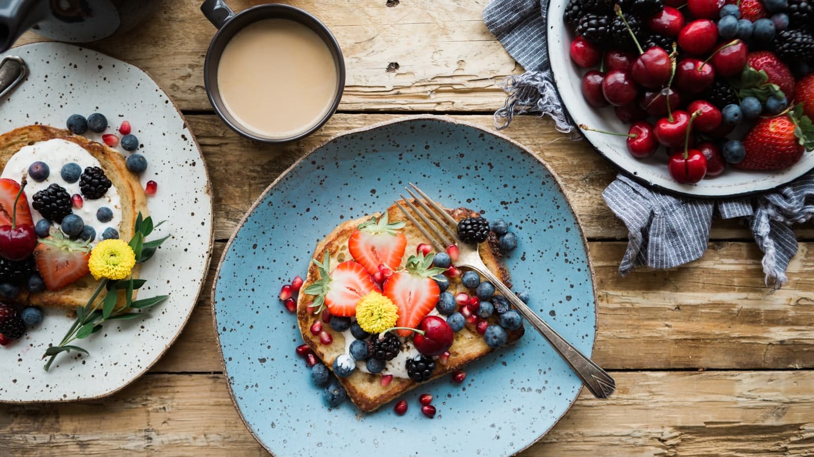 Table de petit-déjeuner en bois avec tartines aux fruits rouges, café et cerises