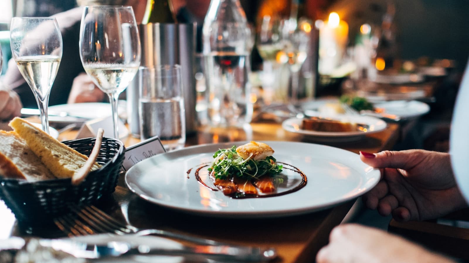 Table de restaurant dressée avec une assiette servie, du pain et des verres de vin