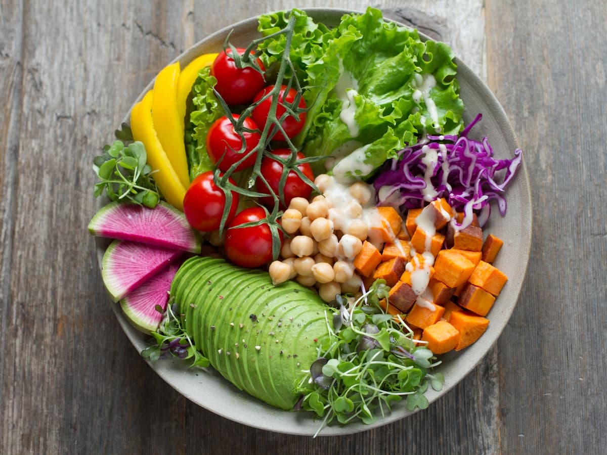 Bol repas coloré composé de légumes frais, avocat, pois chiches et patate douce